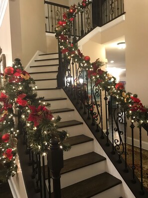A staircase with a garland of lights and red ornaments. - Nashville Get-away, Beautifully furnished, large home, 15 min to downtown Nash! (Goodlettsville)