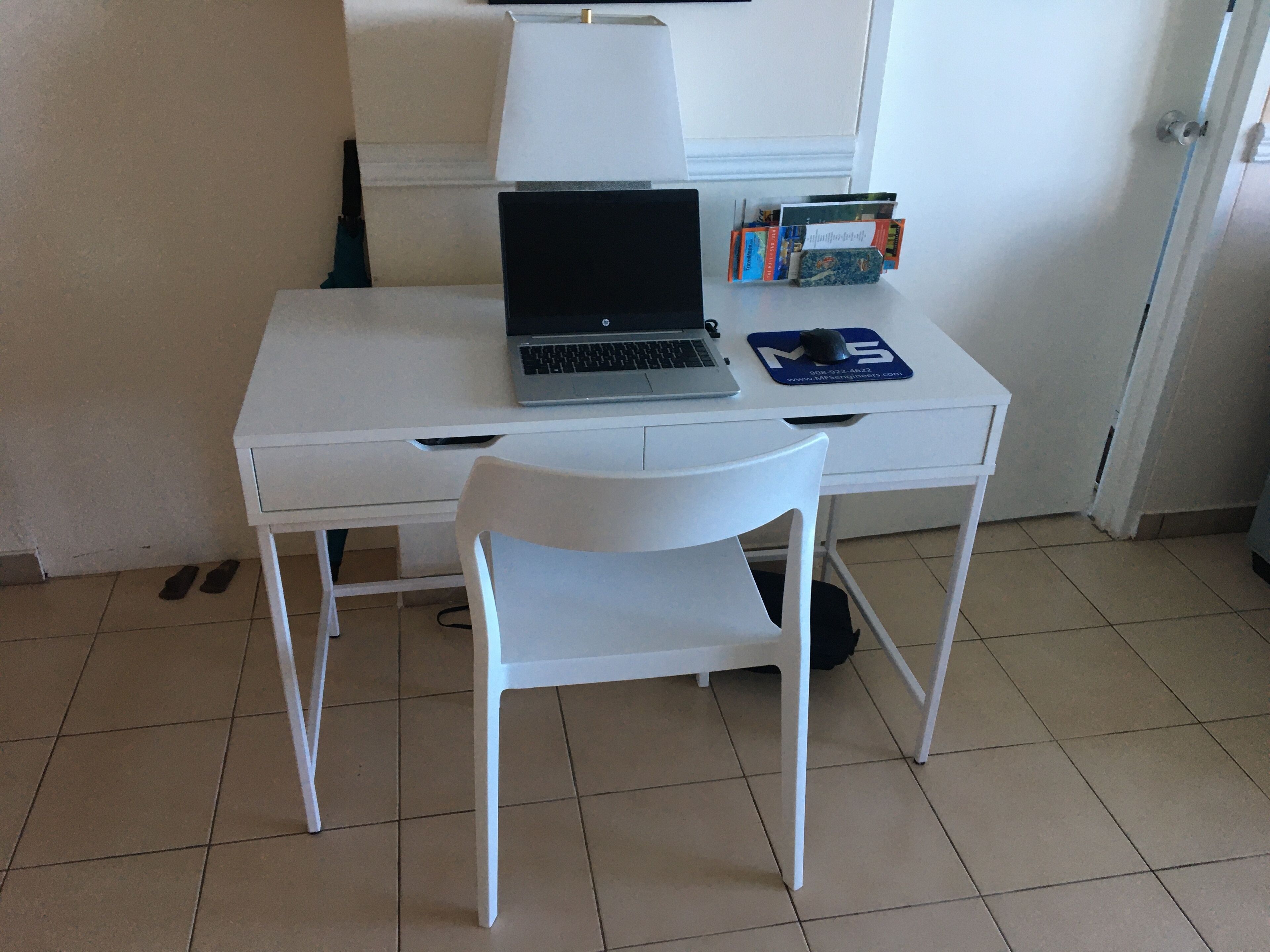 Un escritorio blanco con una computadora portátil, un ratón y un libro.