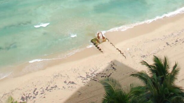 Une plage avec une eau turquoise cristalline et une balançoire installée sur le sable.