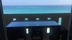 Un balcon avec une table et des chaises, donnant sur une mer turquoise.