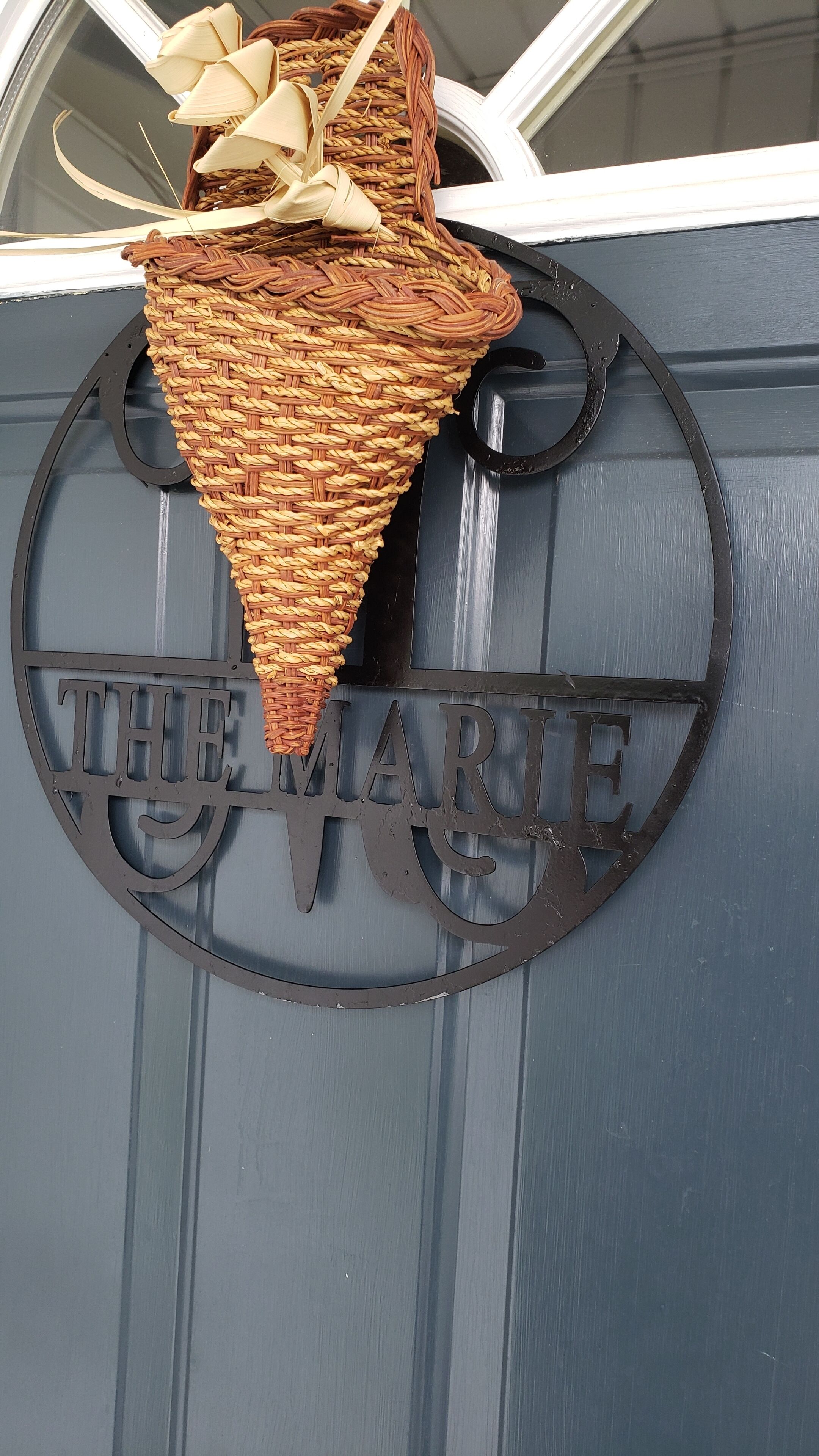 Een metalen bord met de tekst 'THE MARIE' op een donkerblauwe deur.