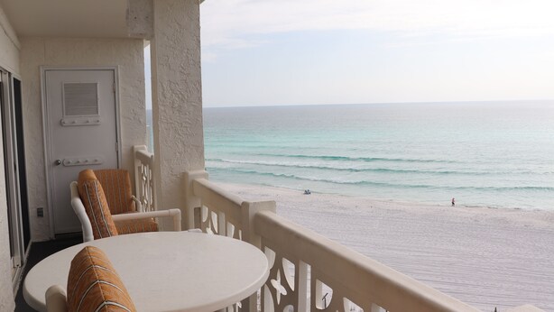 Un balcon donnant sur la plage, une porte et une table avec des chaises.