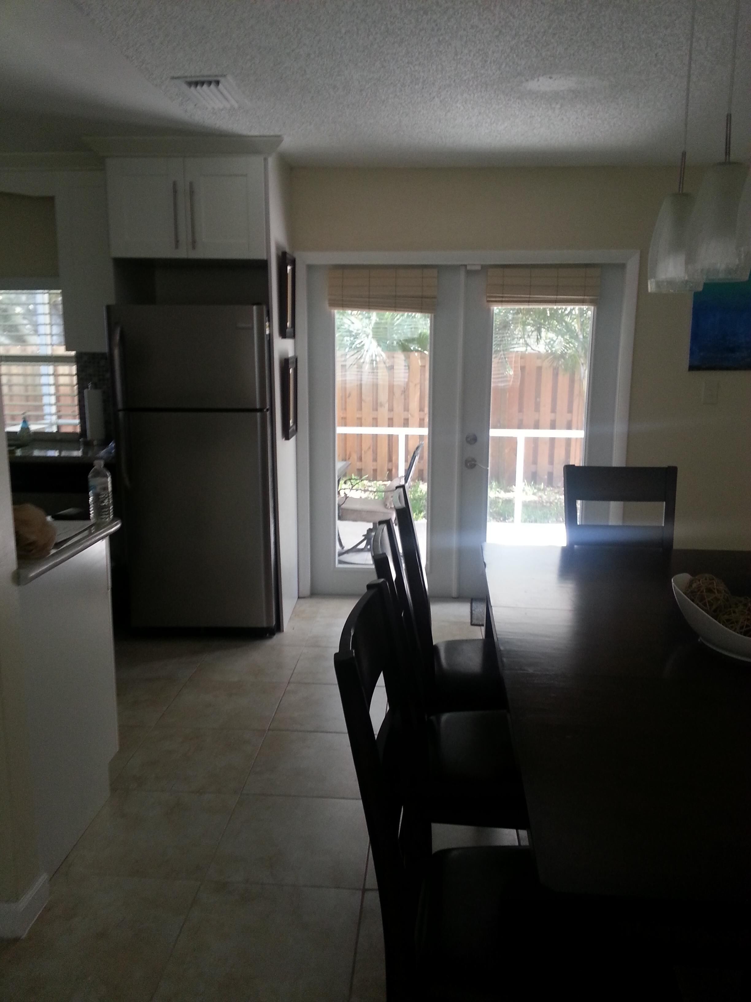 A kitchen with a refrigerator, a dining table with chairs, and a sliding glass door leading to a patio area.