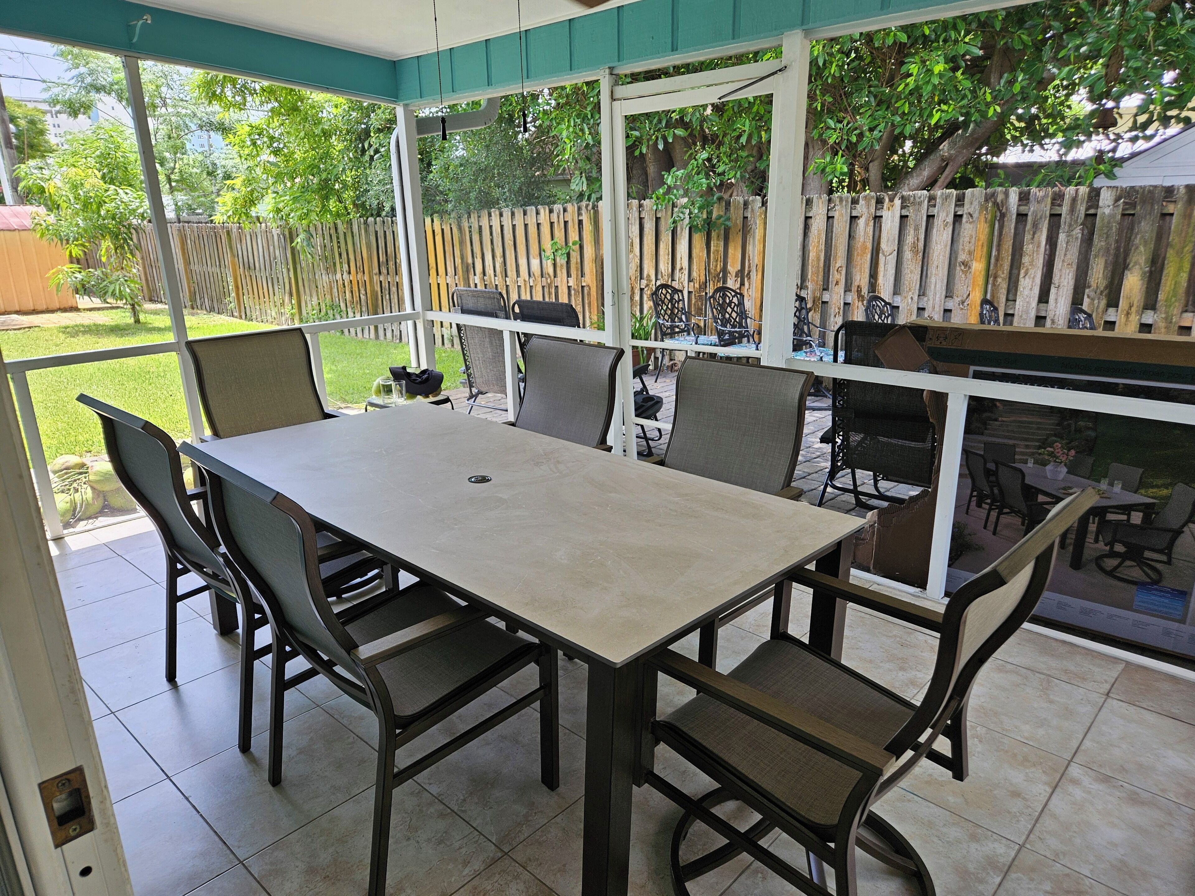 A covered patio with a table and chairs, a wooden fence, and a view of the backyard.