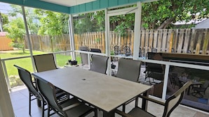 A covered patio with a table and chairs, a wooden fence, and a view of the backyard. - Experience Delray Beach living near vibrant Atlantic Ave! (Delray Beach)