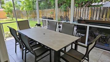 A covered patio with a table and chairs, a wooden fence, and a view of the backyard.