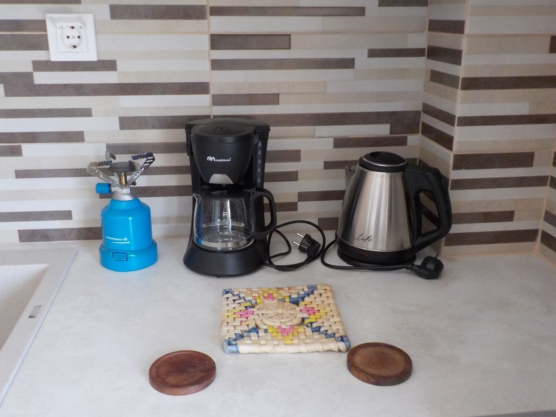 A kitchen with a coffee maker, kettle, and gas stove.