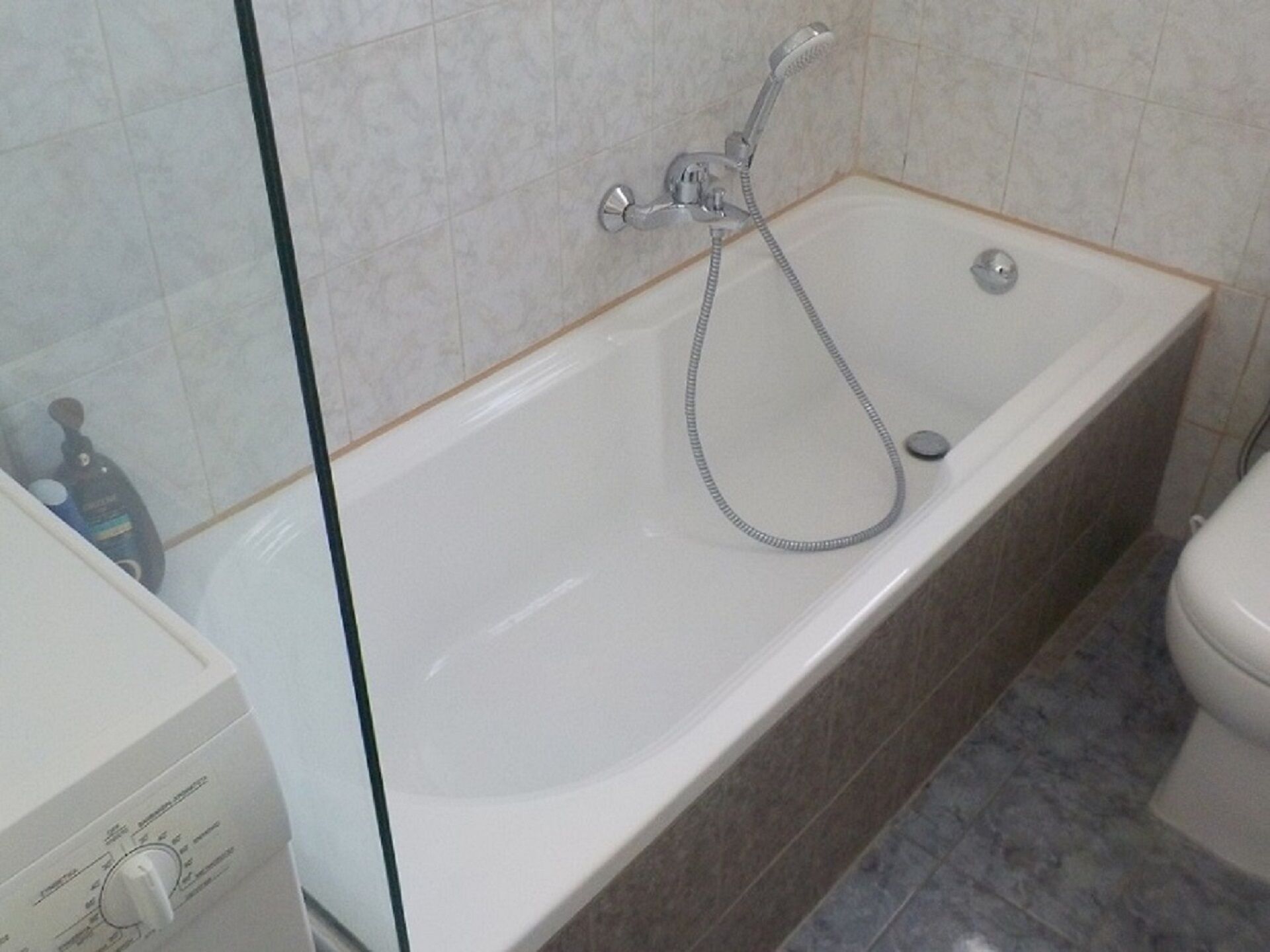 A bathroom with a bathtub, a toilet, and a glass shower enclosure.