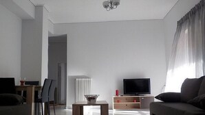Un salon moderne comprenant un canapé, un téléviseur, une table à manger avec des chaises et un radiateur.