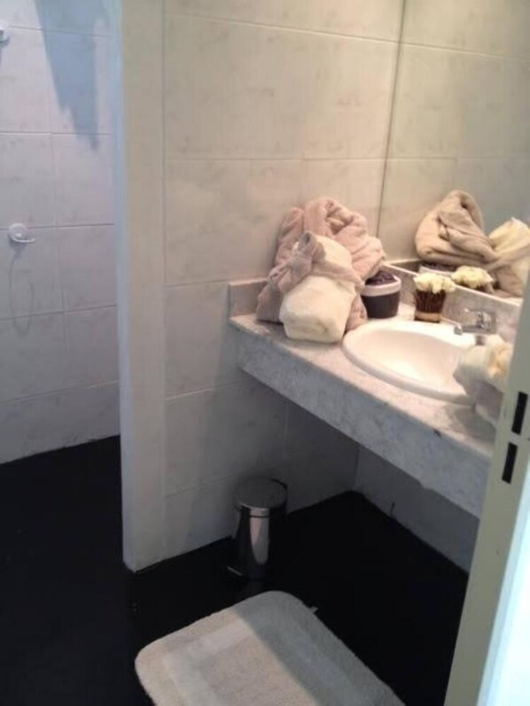 A small bathroom with a white sink, a mirror, and a towel rack. There is a trash can and a small rug on the floor. - House with character (Gordes)