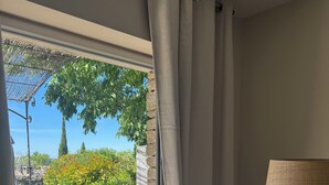 Ein Zimmer mit Blick auf eine Terrasse, einer Lampe und einem Fenster mit Vorhängen.