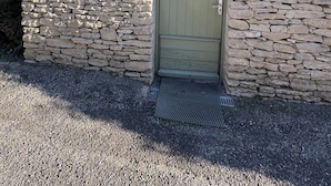 Ein Steinhaus mit einer grünen Tür, einem Schild mit der Aufschrift „BUANDERIE“ und einer verzierten Metallplatte über der Tür.