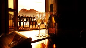 Ein Tisch mit zwei Gläsern, einer Weinflasche, einer Speisekarte und Blick auf Berge durch ein Fenster.