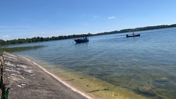 A calm lake with boats, clear water, and a grassy shoreline. - Cottage in Masuria. Mazury famous for its 2,000 lakes. (Gizycko)