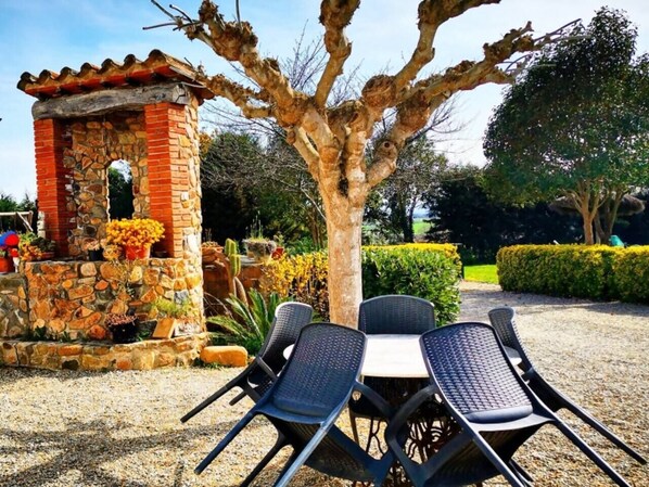 An outdoor seating area with a stone structure, a table, and chairs.