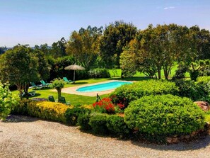 A swimming pool surrounded by well-maintained lawns and trees.