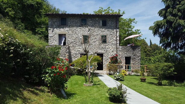 A stone building with a pathway leading to the entrance, surrounded by greenery and flowers. - 3 bedroom house, private pool, gym, mature garden, walk to pizzeria, great views (Cardoso)