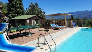 A pool area with lounge chairs, a small building, and a view of mountains. - 3 bedroom house, private pool, gym, mature garden, walk to pizzeria, great views (Cardoso)