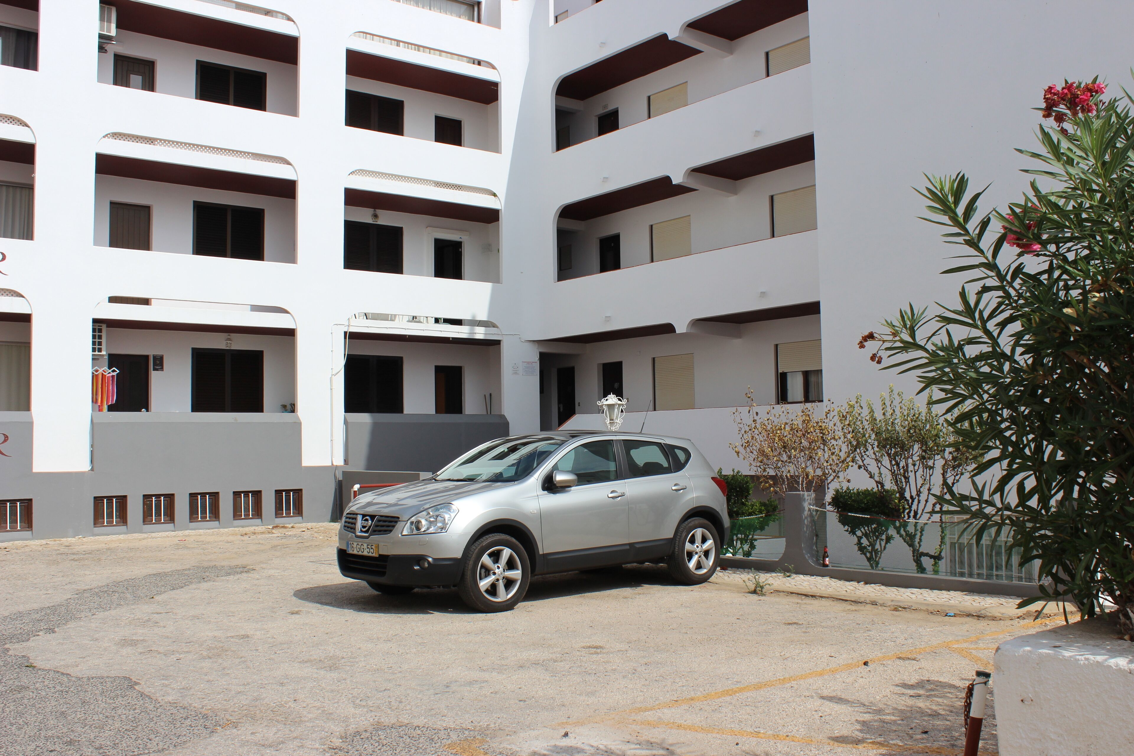 Un SUV plateado estacionado en un estacionamiento, con un edificio de varios pisos al fondo.