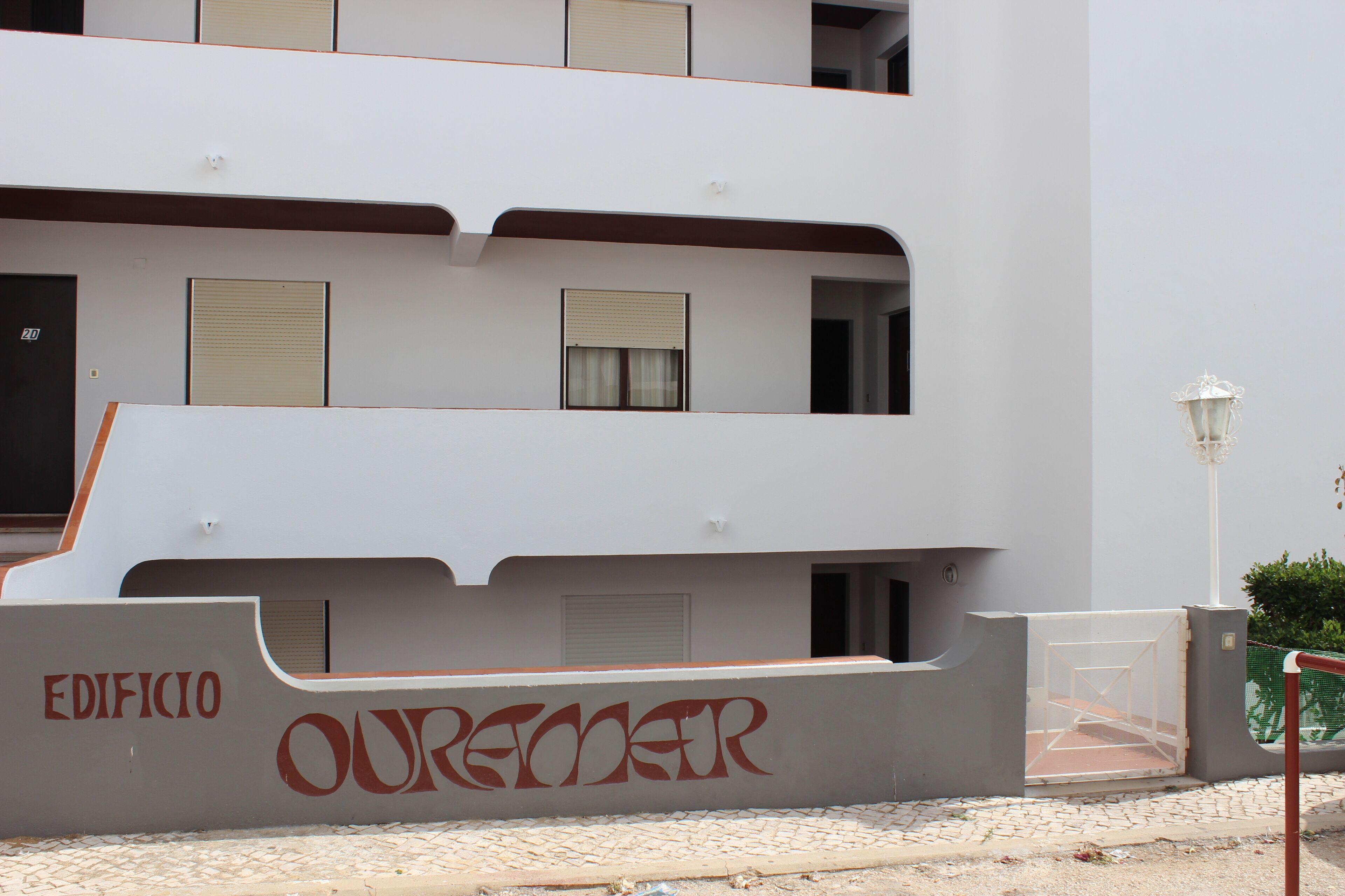 Ein mehrgeschossiges Gebäude mit weißer Fassade, einem gut sichtbaren Eingang und dem Schriftzug "OURENTER" auf dem unteren Teil des Gebäudes.