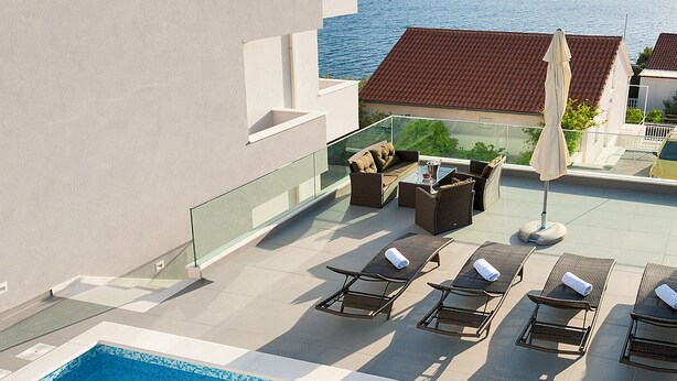 A rooftop pool area with lounge chairs and a view of the sea.