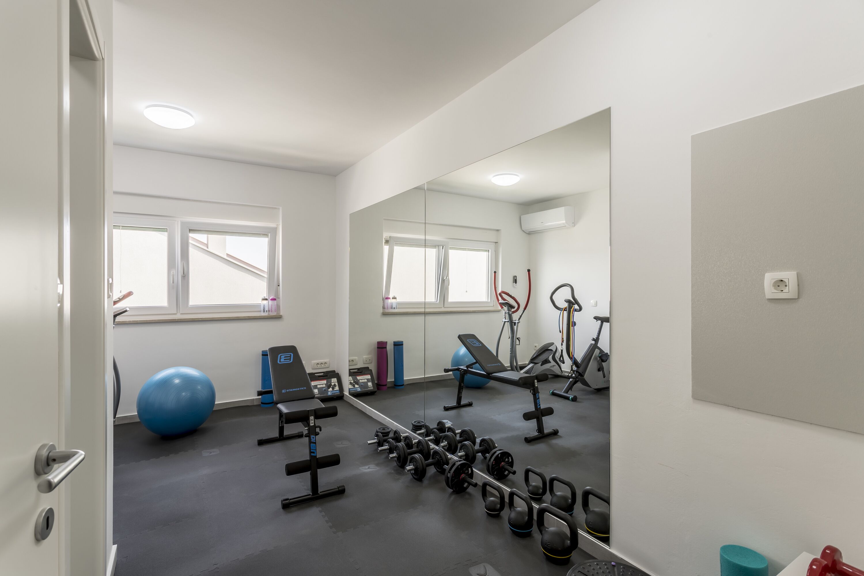 A gym with exercise equipment, a large mirror, and a window.