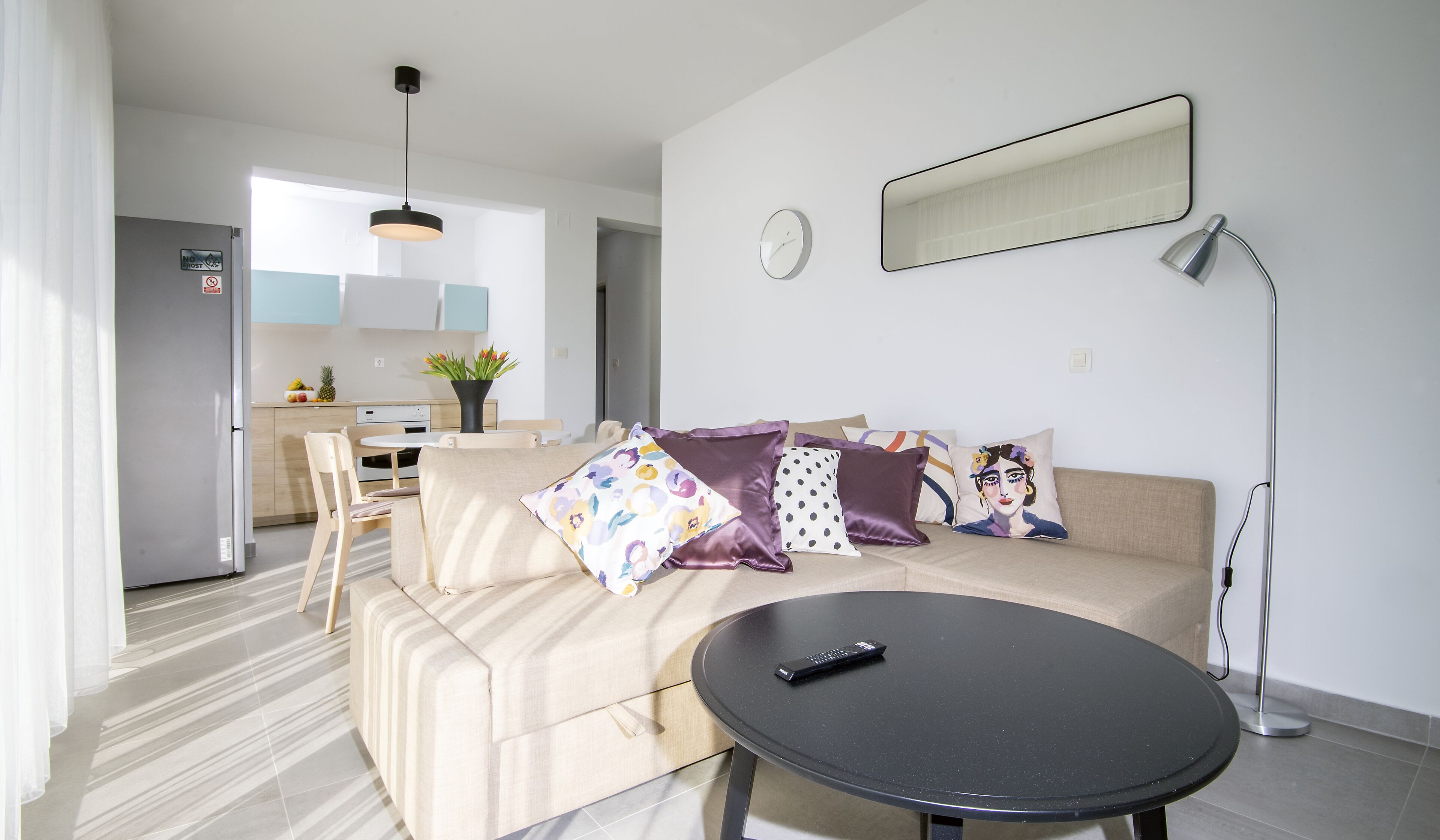 A modern living room with a sofa, a round table, and a remote control.