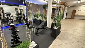 A gym with exercise equipment, benches, and potted plants.