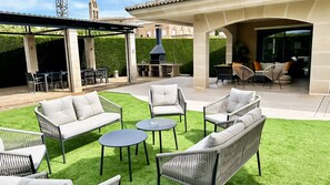 An outdoor patio with wicker furniture, a round table, and a barbecue area.