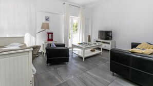 Un salon moderne avec un canapé, une table basse, un téléviseur et une lampe.