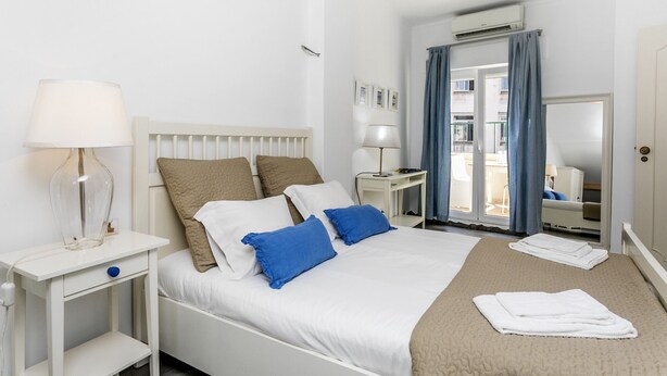 Une chambre d’hôtel avec un lit, des tables de chevet, un bureau et une fenêtre avec des rideaux.