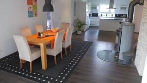 Eine moderne Küche mit einer zentralen Kochinsel, einem Essbereich mit Tisch und Stühlen sowie einem sichtbaren Herd.