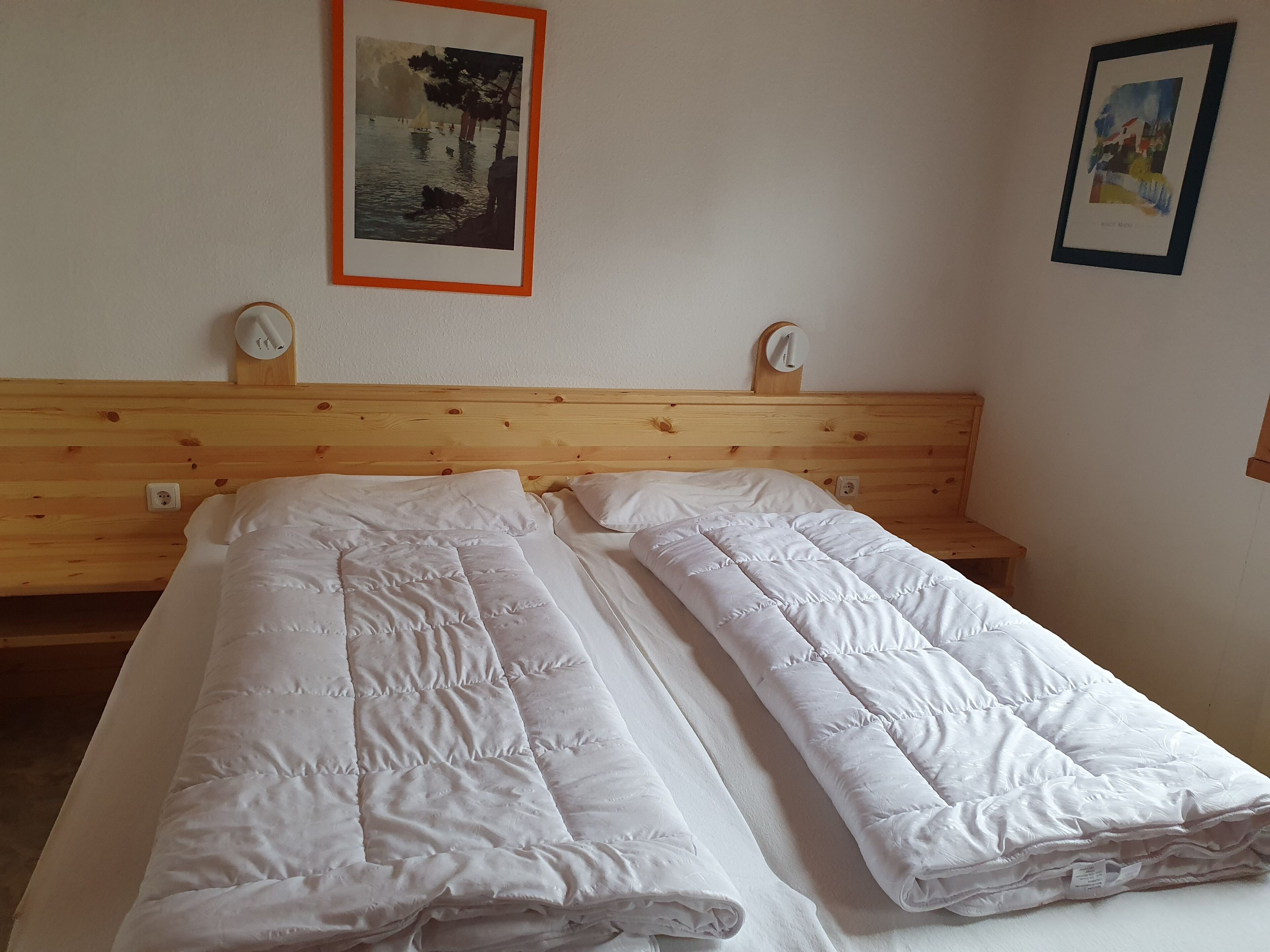 A double bed with white bedding, a wooden headboard, and two bedside tables with wall clocks.