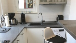 A compact kitchen with a sink, stove, and two bar stools.
