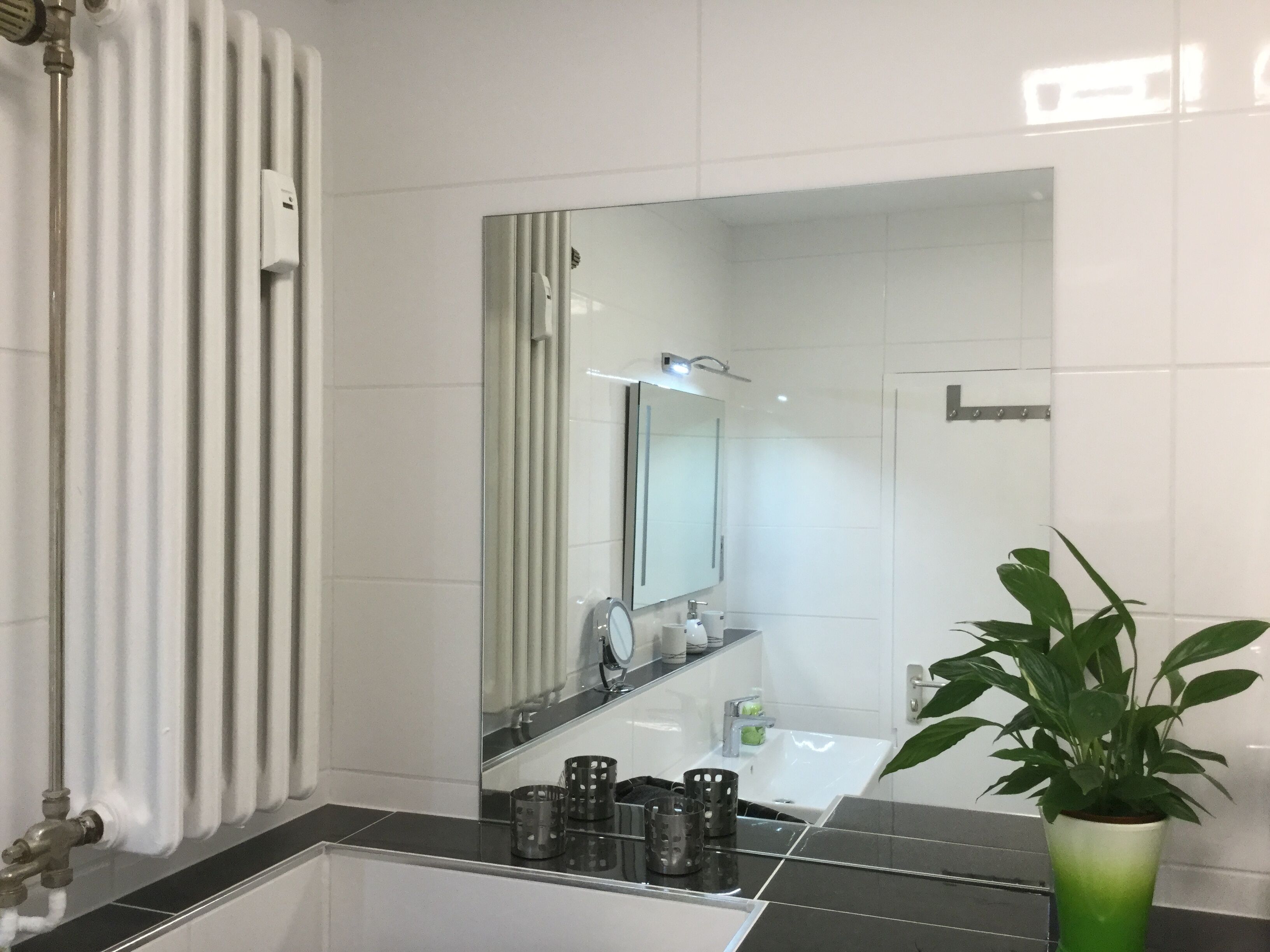Un baño moderno con un espejo grande, un lavamanos y un radiador.