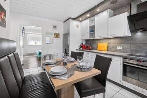 Une cuisine moderne avec des meubles blancs, une table à manger en bois et un four noir.