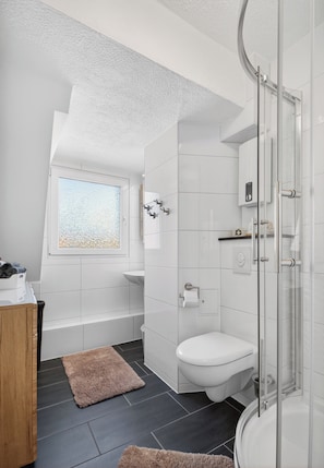 A modern bathroom with a shower, toilet, and bathtub.