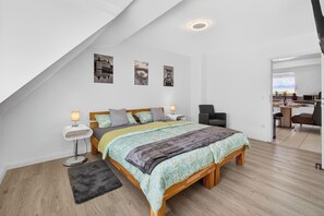 Une chambre à coucher avec un lit, des tables de chevet, une chaise et un bureau.