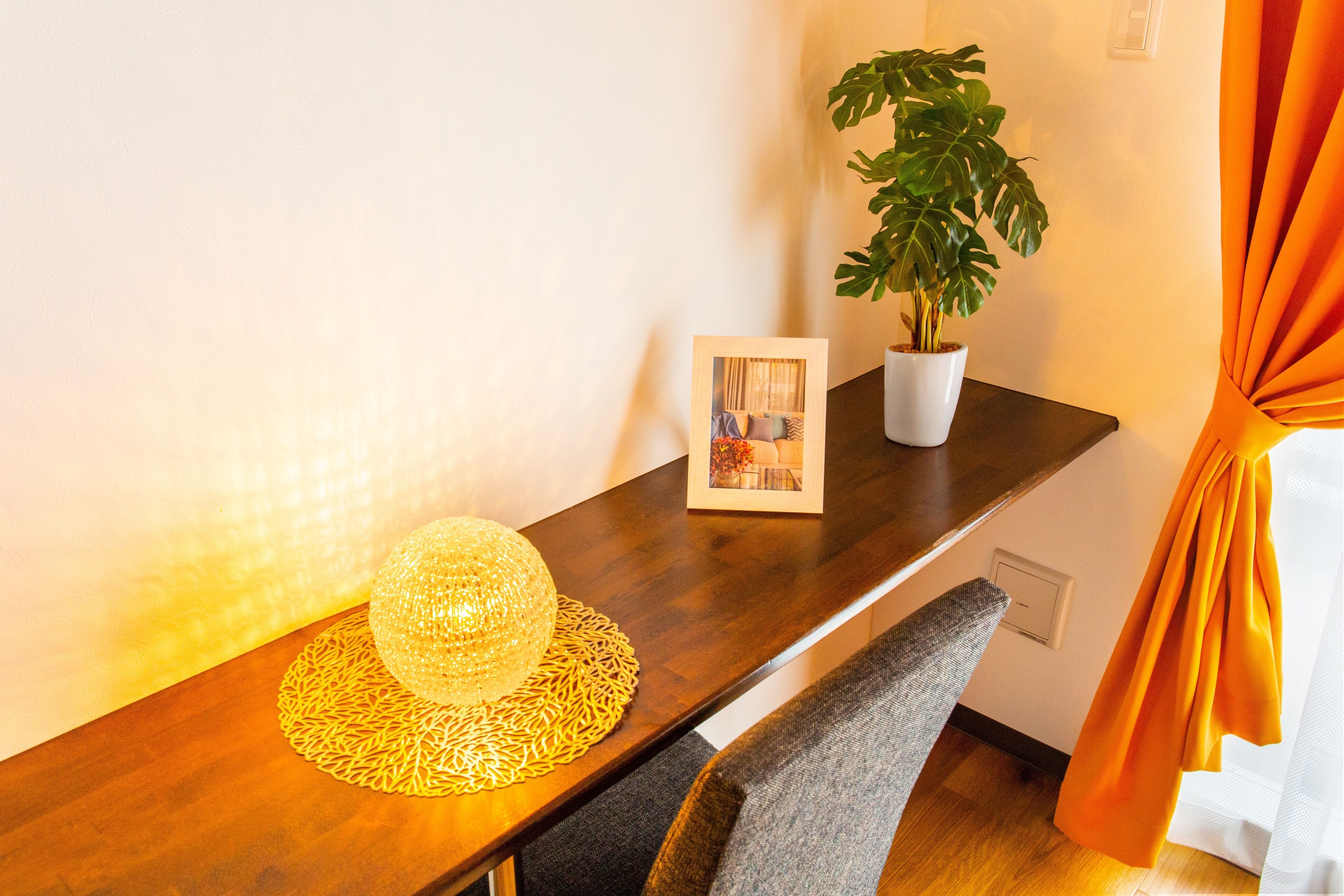 A wooden table with a decorative light, a framed picture, and a potted plant.