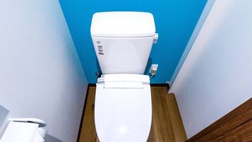 A white toilet with a blue wall and wooden floor in a bathroom.