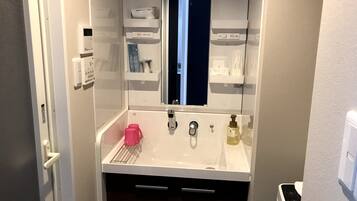 A compact bathroom with a white sink, a mirror, a window, and a door.