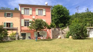 A two-story building with a stone staircase leading to a door, surrounded by a grassy lawn and trees. - Castellane the Verdon Gorges Grand new studio  (Castellane)