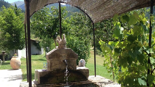A water feature with a stone structure and a thatched roof. - Castellane the Verdon Gorges Grand new studio  (Castellane)