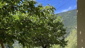 A patio with a round table and chairs, surrounded by trees and a view of a green field and hills. - Castellane the Verdon Gorges Grand new studio  (Castellane)