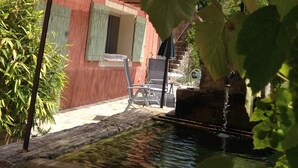 A courtyard with a water feature, a pergola, and a building with a red facade and green shutters. - Castellane the Verdon Gorges Grand new studio  (Castellane)