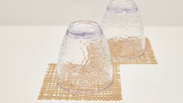 Two clear glass vases with intricate patterns on a golden woven placemat.