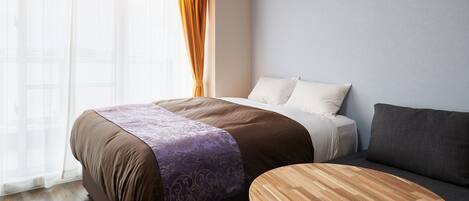 Una habitación de hotel moderna con una cama grande, una mesita de madera y un sofá.