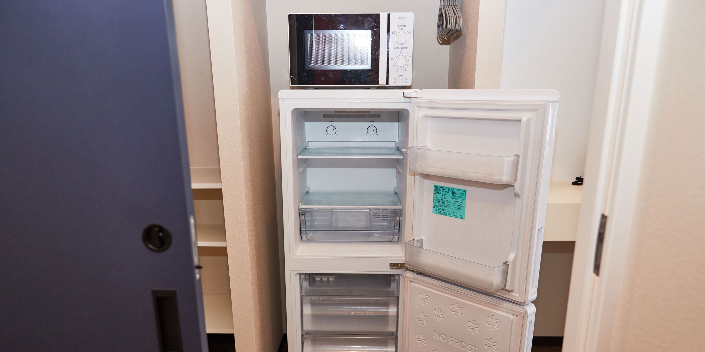A compact kitchen with a microwave, a refrigerator, and a freezer.