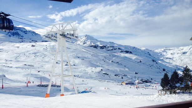 Un telesilla en una montaña nevada con una barandilla de madera al frente.