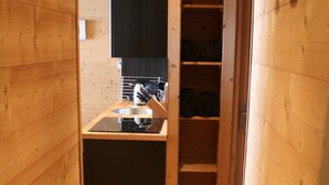 Un estrecho pasillo de madera que desemboca en una zona de cocina, con un fregadero, estufa y estanterías.